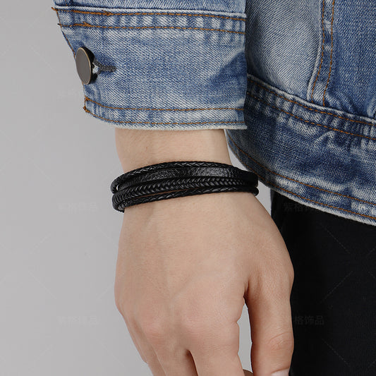 Homme portant bracelet multi-rangs cuir tressé noir minimaliste au poignet avec veste en denim